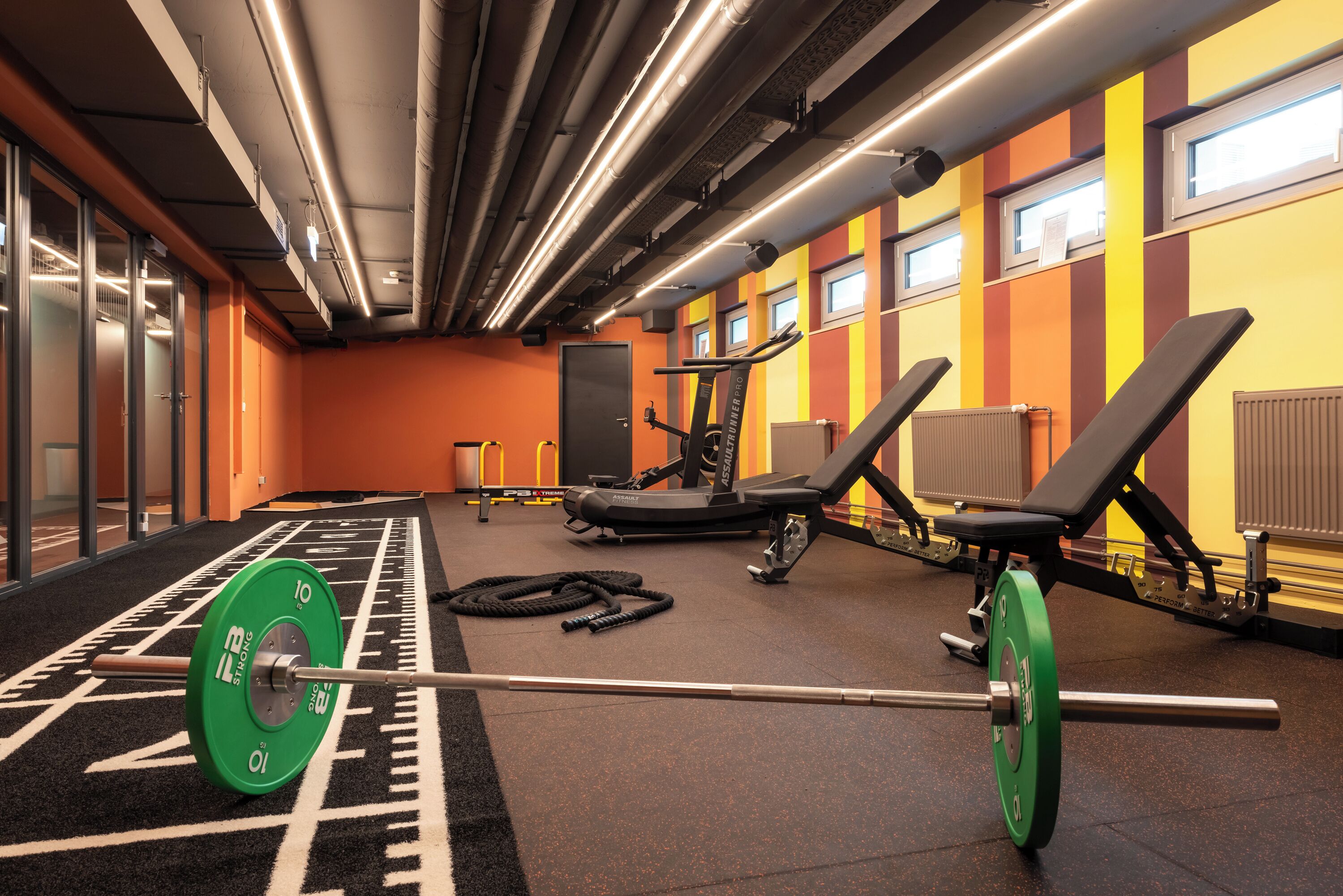 A gym with weightlifting equipment, treadmills, and benches.