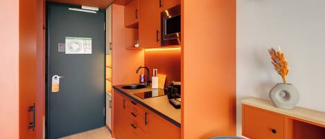 A compact kitchen with a microwave, sink, and cabinets.