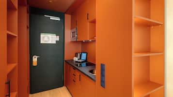 Eine kleine Küche mit einer Mikrowelle, einer digitalen Waage und einer Kaffeemaschine auf der Arbeitsfläche.