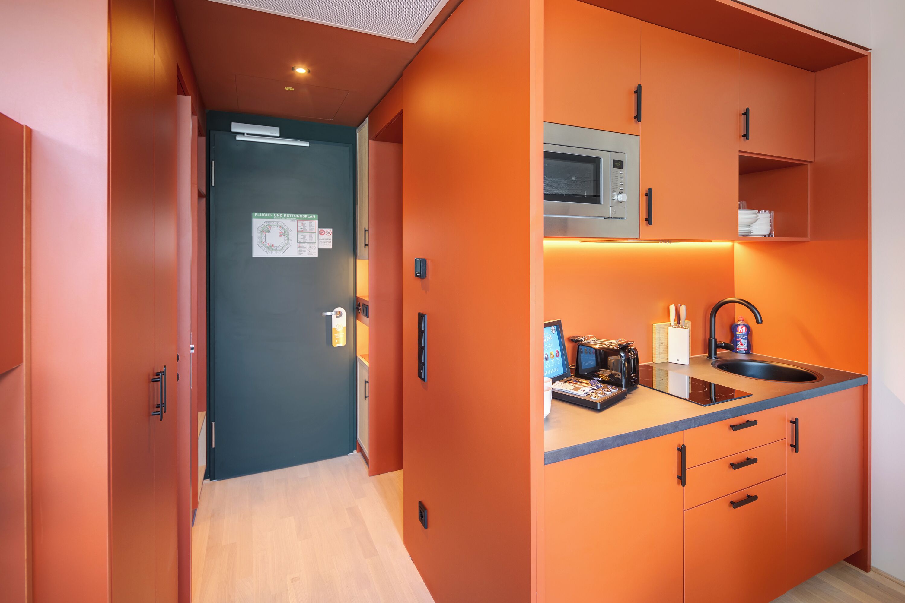 Cocina compacta con microondas, pileta y electrodomésticos sobre la encimera.