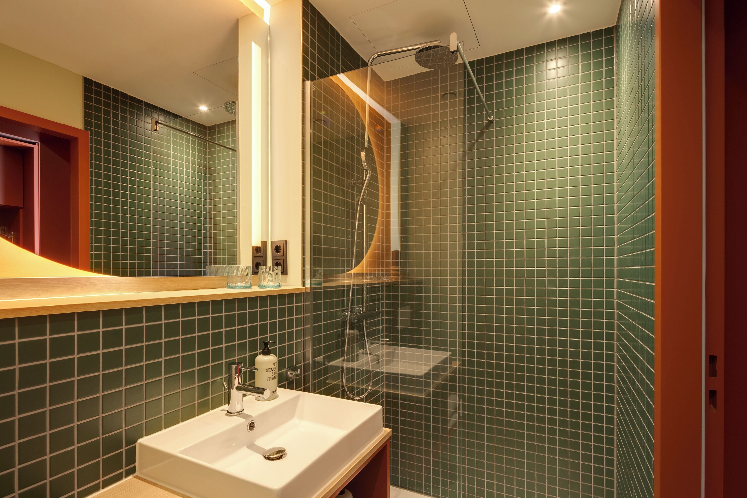 Een badkamer met wastafel, spiegel en douche.