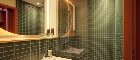 Een badkamer met wastafel, spiegel en douche.