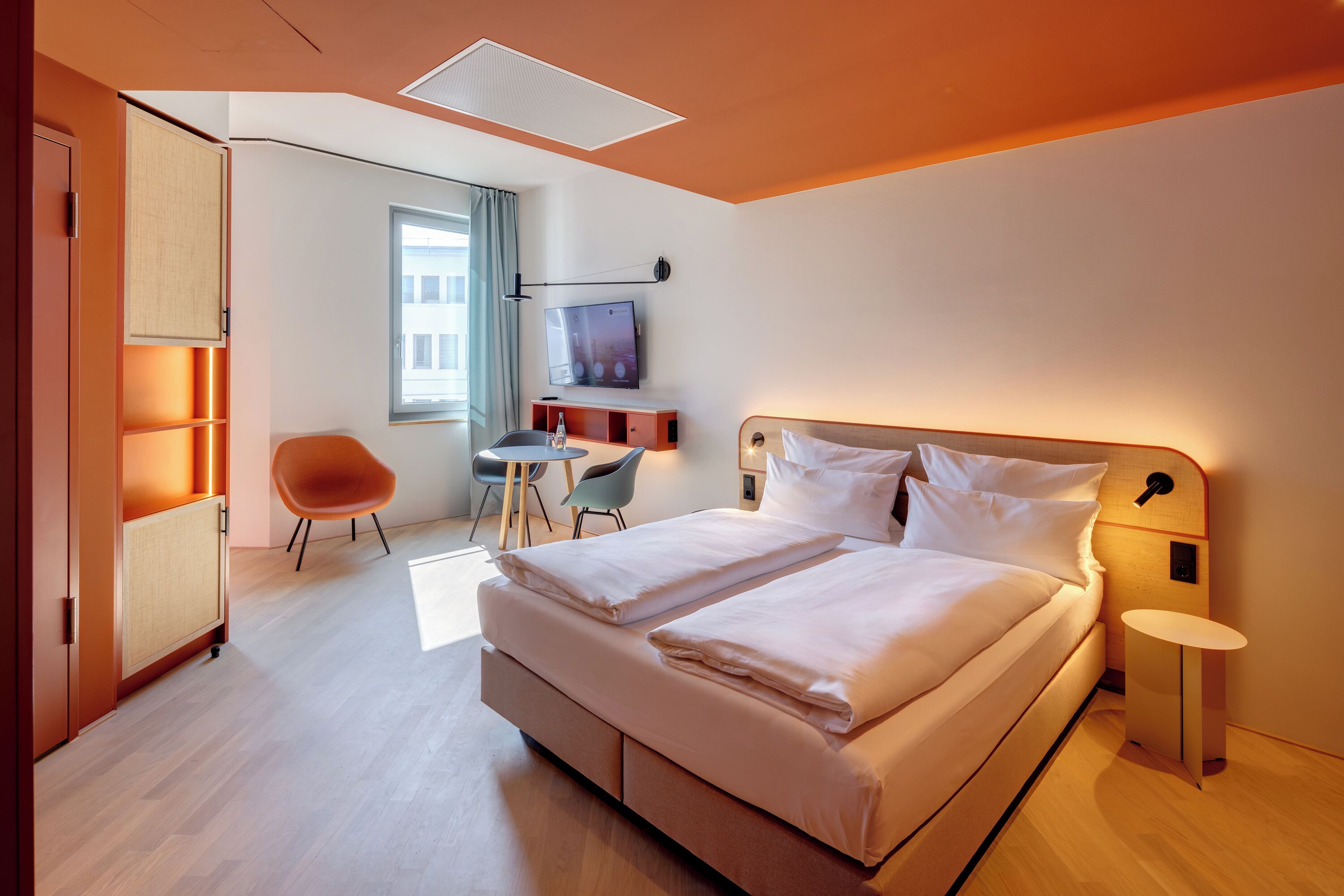 Una habitación de hotel moderna con una cama grande, un escritorio, una silla y un televisor.