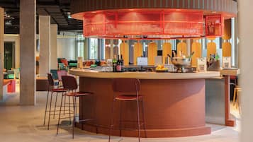A modern bar area with a curved counter, stools, and a red overhead structure.