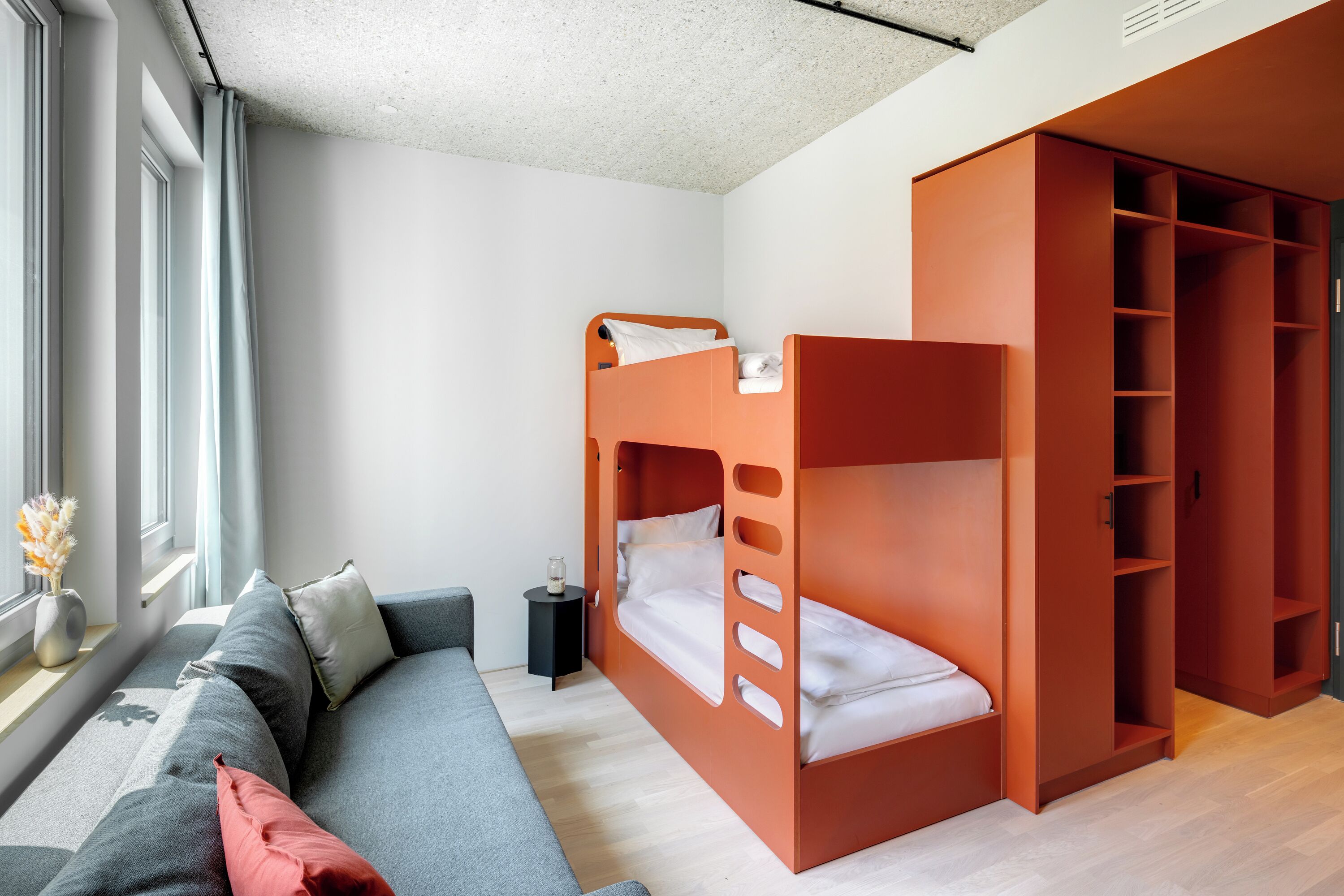 Une chambre moderne avec un lit superposé, un canapé et une armoire.