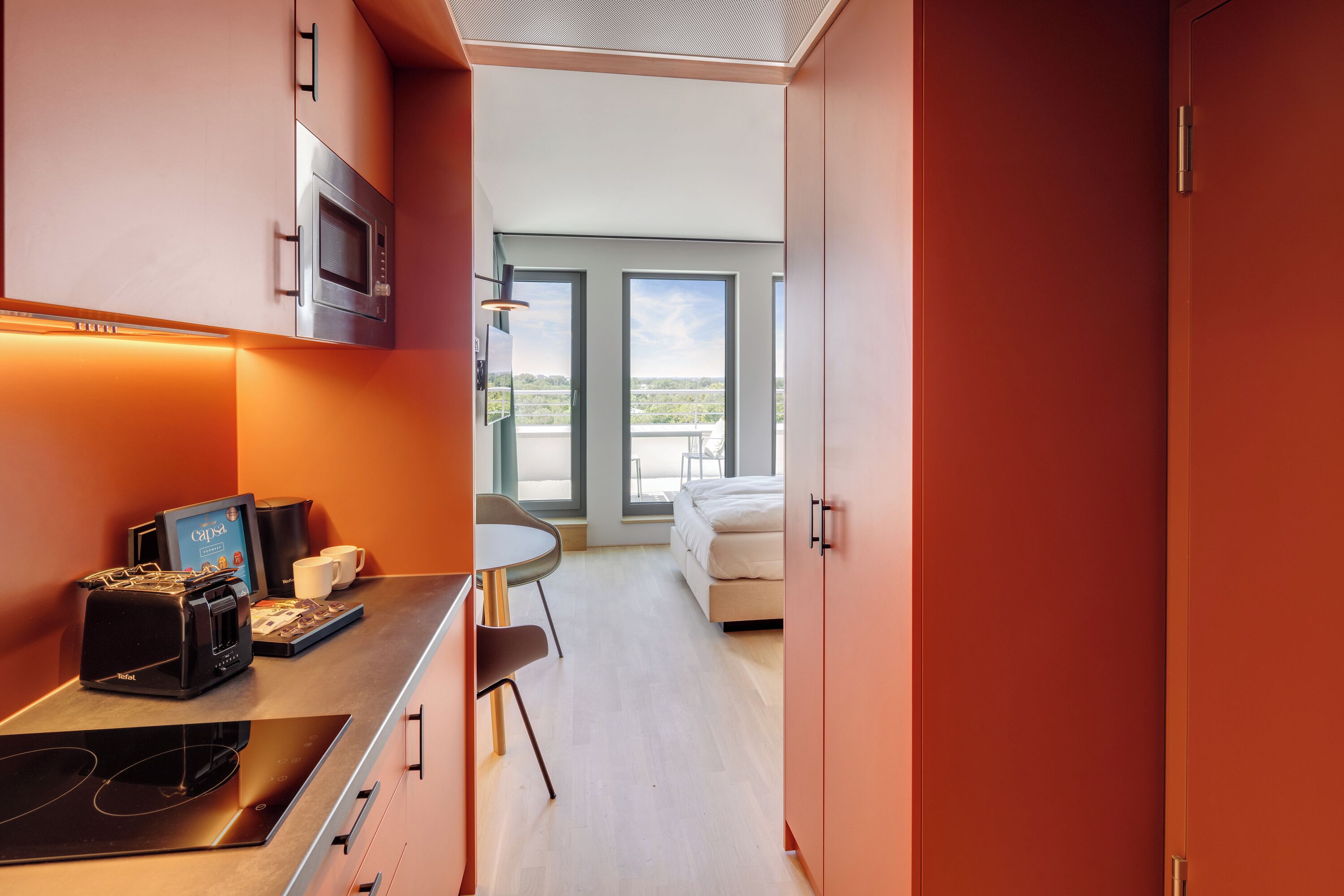 A modern kitchen with a built-in microwave, coffee machine, and a dining area with a table and chairs.