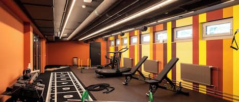 Un gimnasio con equipo de ejercicio, una banca de pesas y una cinta de correr.