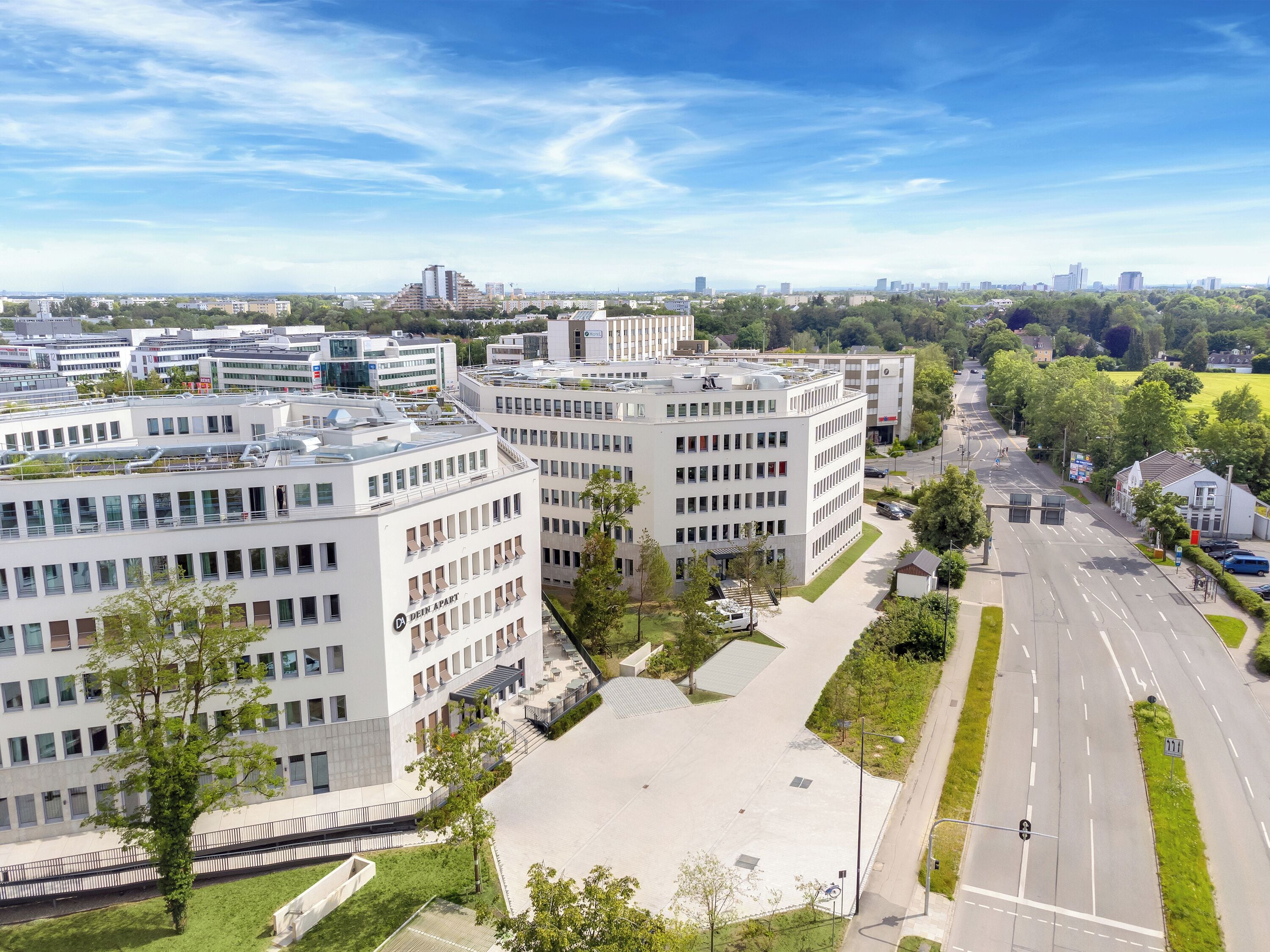 Een modern gebouwcomplex met meerdere verdiepingen, grote ramen en een ruime binnenplaats.