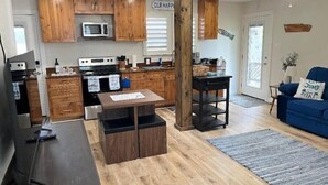 Una cocina moderna con armarios de madera, un microondas y un comedor con mesa y bancos.