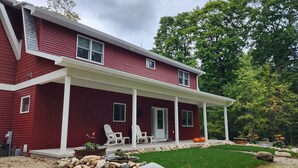 Une maison rouge à deux étages, dotée d’un porche abrité, de colonnes blanches et d’une pelouse bien entretenue.