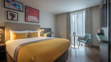 A hotel room with a large bed, a small round table, a chair, and a television.