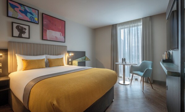 A hotel room with a large bed, a small round table, a chair, and a television. - Maldron Hotel Manchester Central – Cathedral Quarter (Salford)