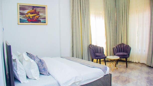 Una habitación de hotel con una cama, una silla, una mesita y un cuadro en la pared.
