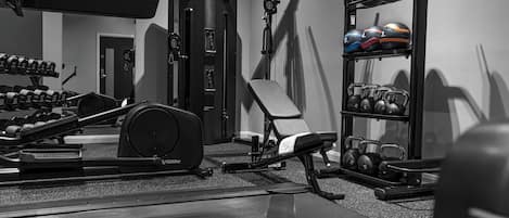 A gym with weight machines, dumbbells, and a bench.