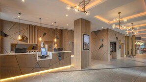 A modern reception desk with a digital check-in station, geometric wall design, and ambient lighting.