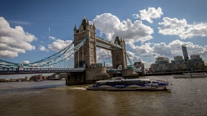 The Tower Bridge in London with a boat in the foreground and modern buildings in the background. - Maldron Hotel Shoreditch London (London)