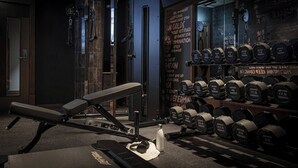 A gym with a bench press, various dumbbells, and motivational quotes on the wall. - Maldron Hotel Shoreditch London (London)