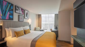 Habitació d'hotel amb un llit gran, un escriptori, una cadira i una televisió.