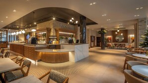 A modern restaurant with a central bar area, seating around it, and a patterned floor. - Maldron Hotel Shoreditch London (London)
