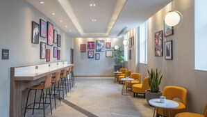 A modern interior with a bar area, seating, and artwork on the walls. - Maldron Hotel Brighton City Centre (Brighton)