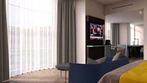 A modern hotel room with a large window, a flat-screen TV, a desk with a laptop, and a comfortable seating area. - Maldron Hotel Brighton City Centre (Brighton)