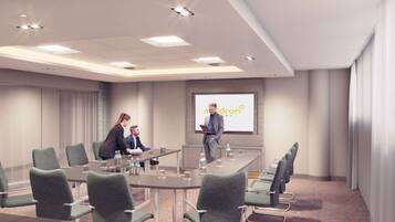 A conference room with a long table, multiple chairs, and a presentation screen displaying 'maldron hotel'.