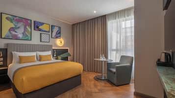 Ein Hotelzimmer mit einem Bett, einem Sessel, einem kleinen Tisch und Bildern an der Wand.