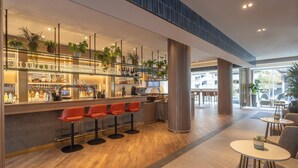 A modern bar area with a wooden floor, bar stools, and shelves with bottles and glasses. - Maldron Hotel Brighton City Centre (Brighton)