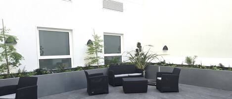 A modern outdoor seating area with wicker furniture and a low wall.