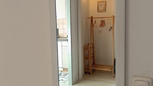 Een hal met een houten rek, een lijst met een foto aan de muur en een deur naar een andere kamer.