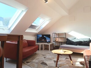 A loft-style living room with a television, red leather sofa, a wooden coffee table, and a geometric-patterned rug. - Super apartment #4 in the center near Stolberg Castle (Stolberg)