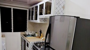 A compact kitchen with a refrigerator, stove, oven, and cabinets. - Apto, Res, Carmen Renata Iii, a 8 Minutos de la Embajada Americana sto dgo (Pantoja)