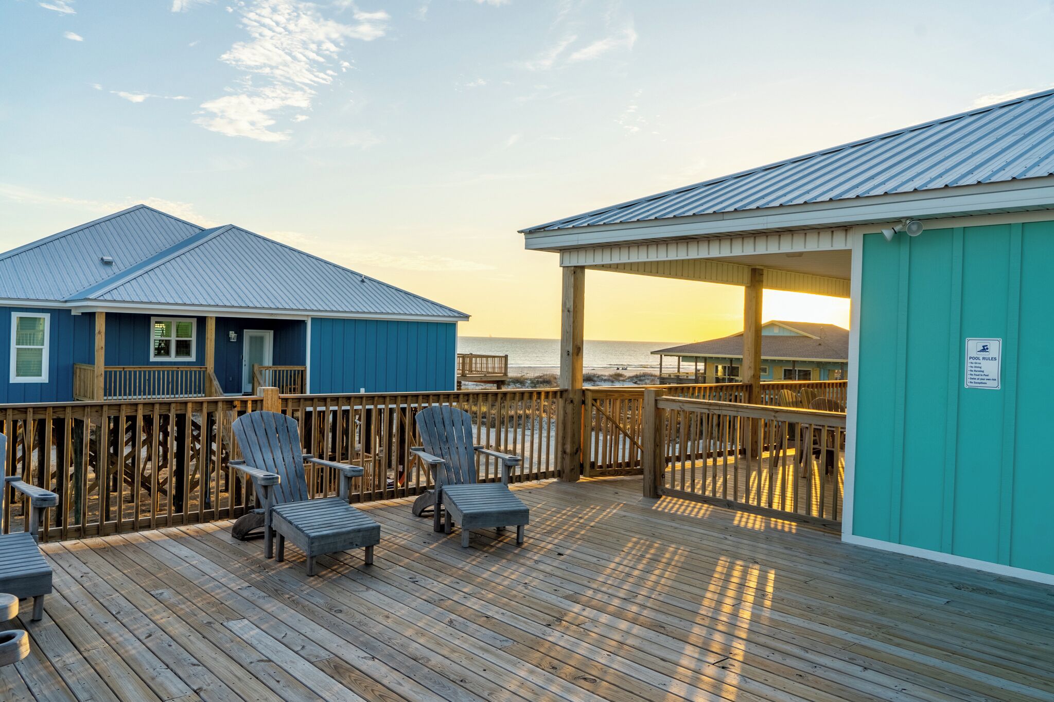 A wooden deck with chairs and a view of the ocean.
