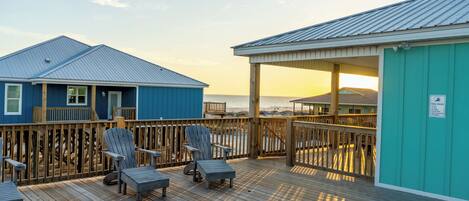 A wooden deck with chairs and a view of the ocean.