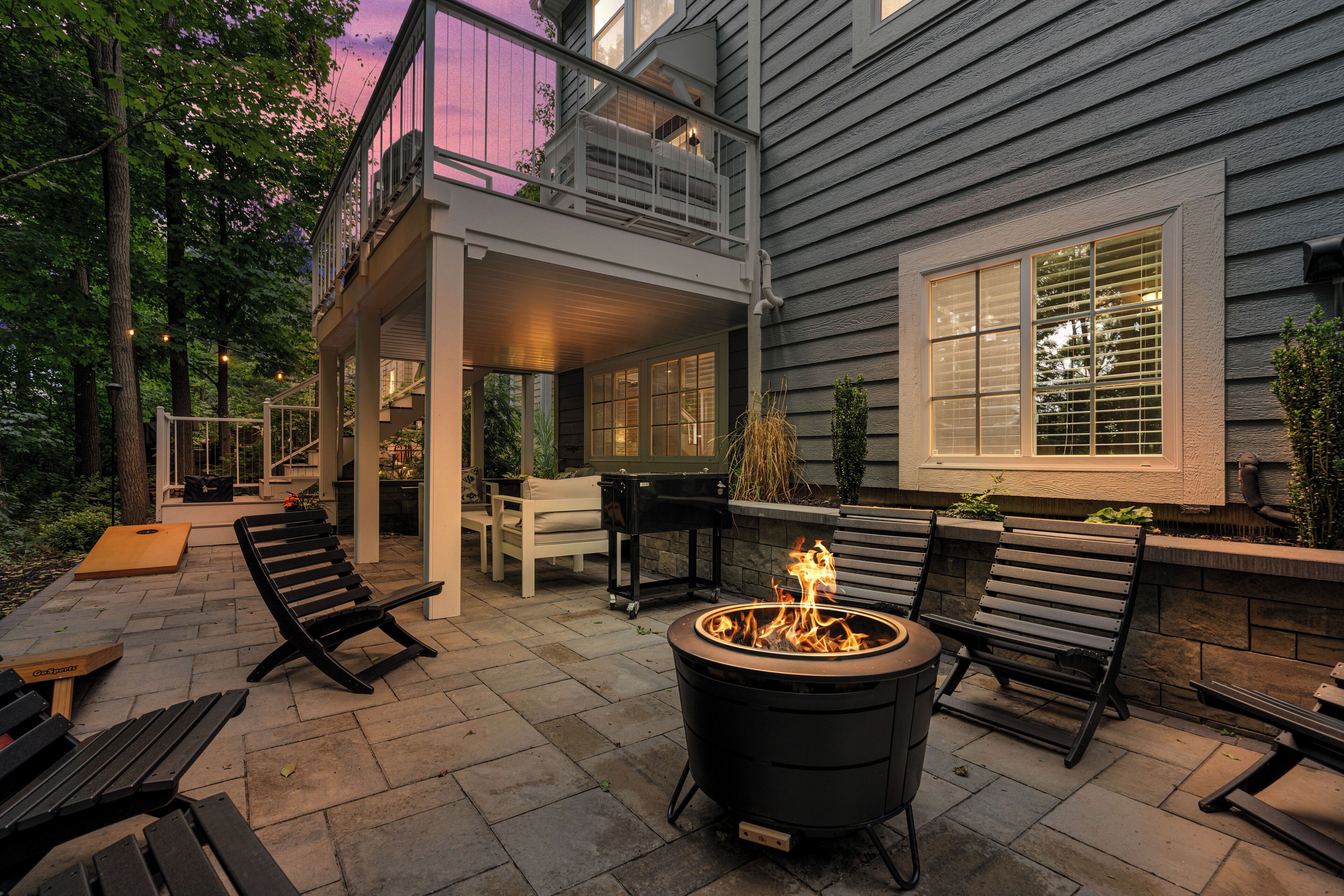 An outdoor patio with a fire pit, benches, and a covered seating area.