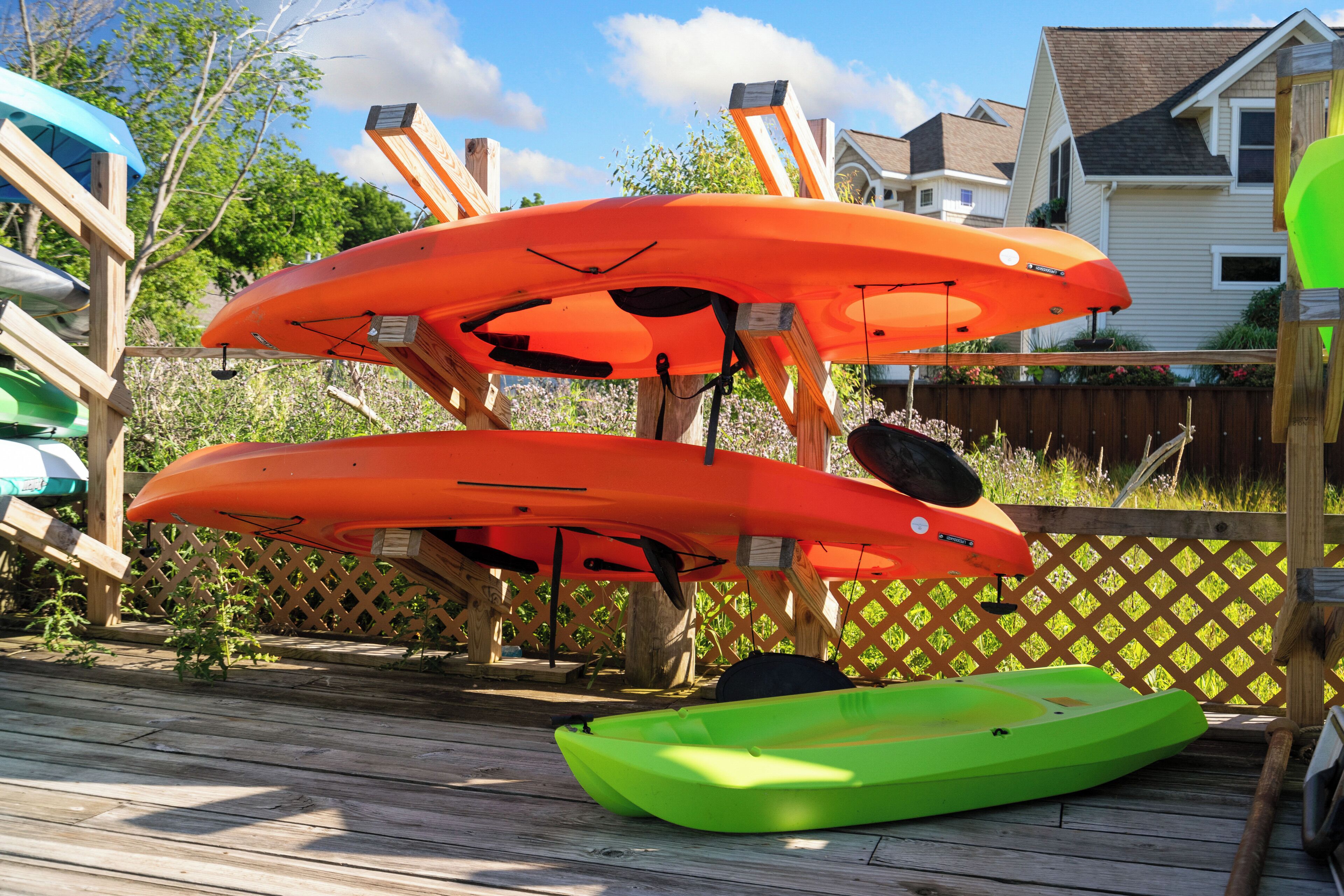 Une terrasse en bois avec des kayaks et une planche de paddle.