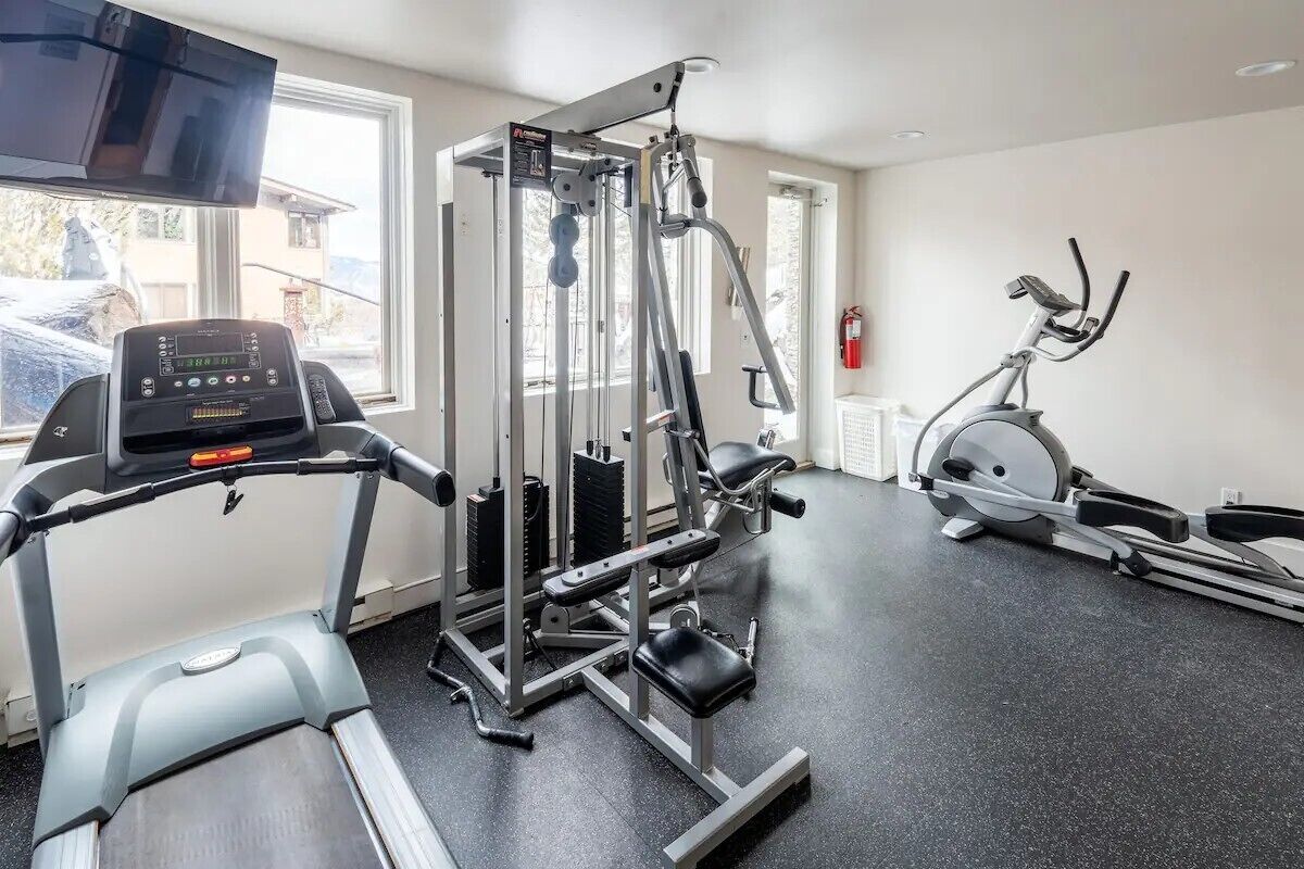 Kuntosali, jossa on juoksumatto, painonnostolaite ja crosstrainer.