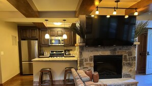 Una cucina moderna con camino in pietra, mobili in legno e una grande TV.
