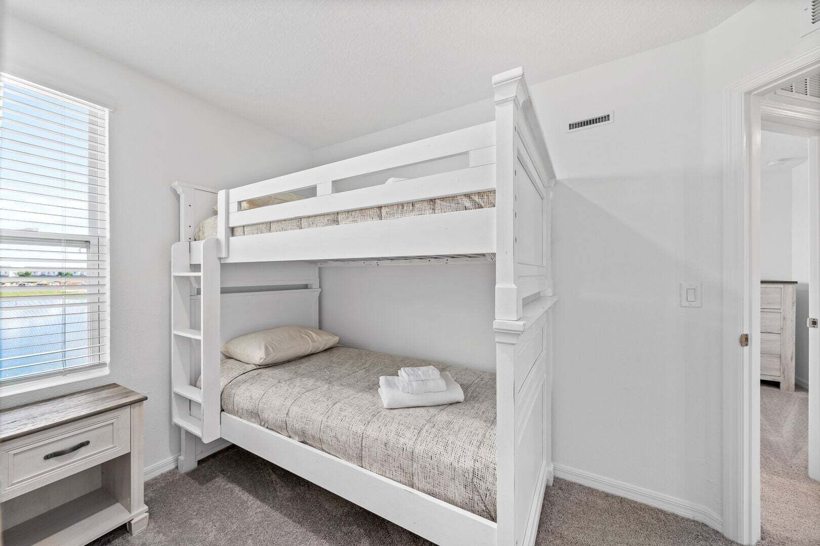 A bunk bed room with a desk and a window.