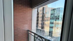 Un balcon avec une balustrade en métal, un mur en briques et une vue sur des immeubles.