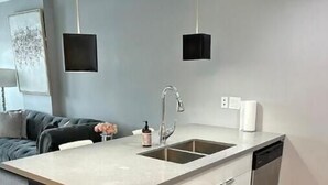 Une cuisine moderne dotée d’un îlot central, d’un évier en acier inoxydable et d’un lave-vaisselle.