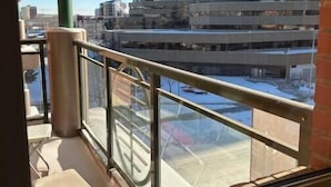 A balcony with a view of a parking garage and a tall building in the background.