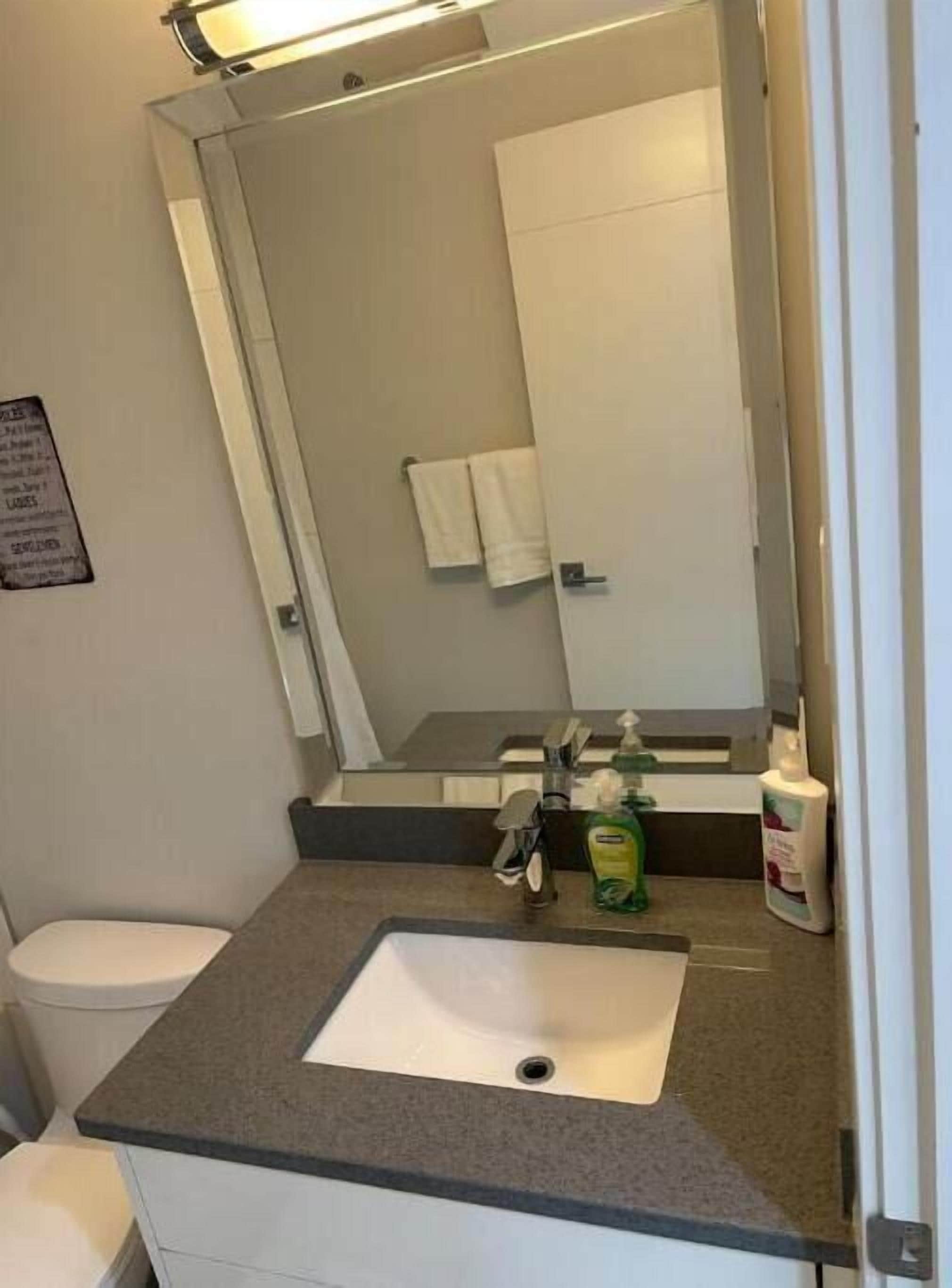 Un bagno con un lavandino bianco, uno specchio e un asciugamano appeso al muro.
