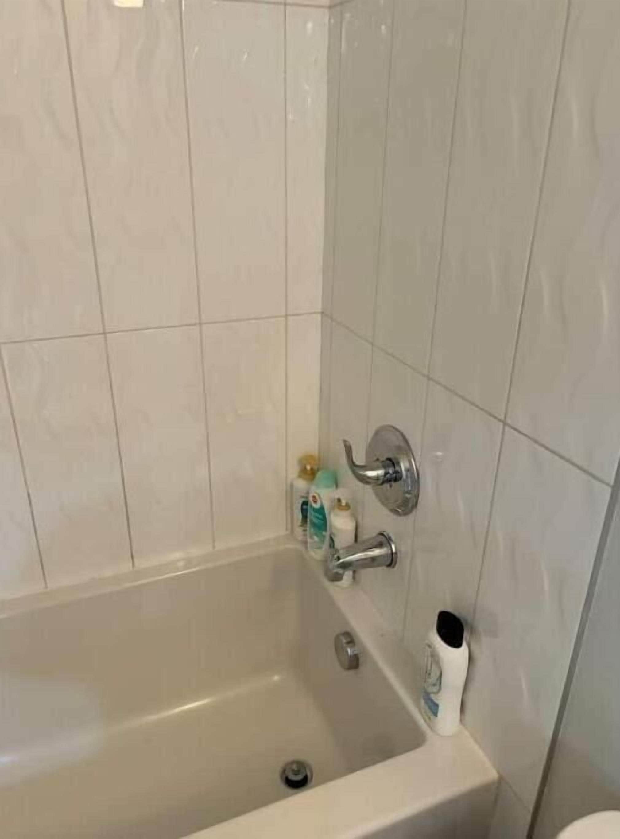 A bathroom with a bathtub, a toilet, and a sink. There are toiletries on the wall.
