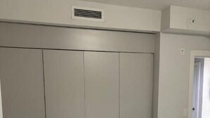 A bedroom with a large wardrobe, a bed with a white duvet, and a marble-patterned floor.