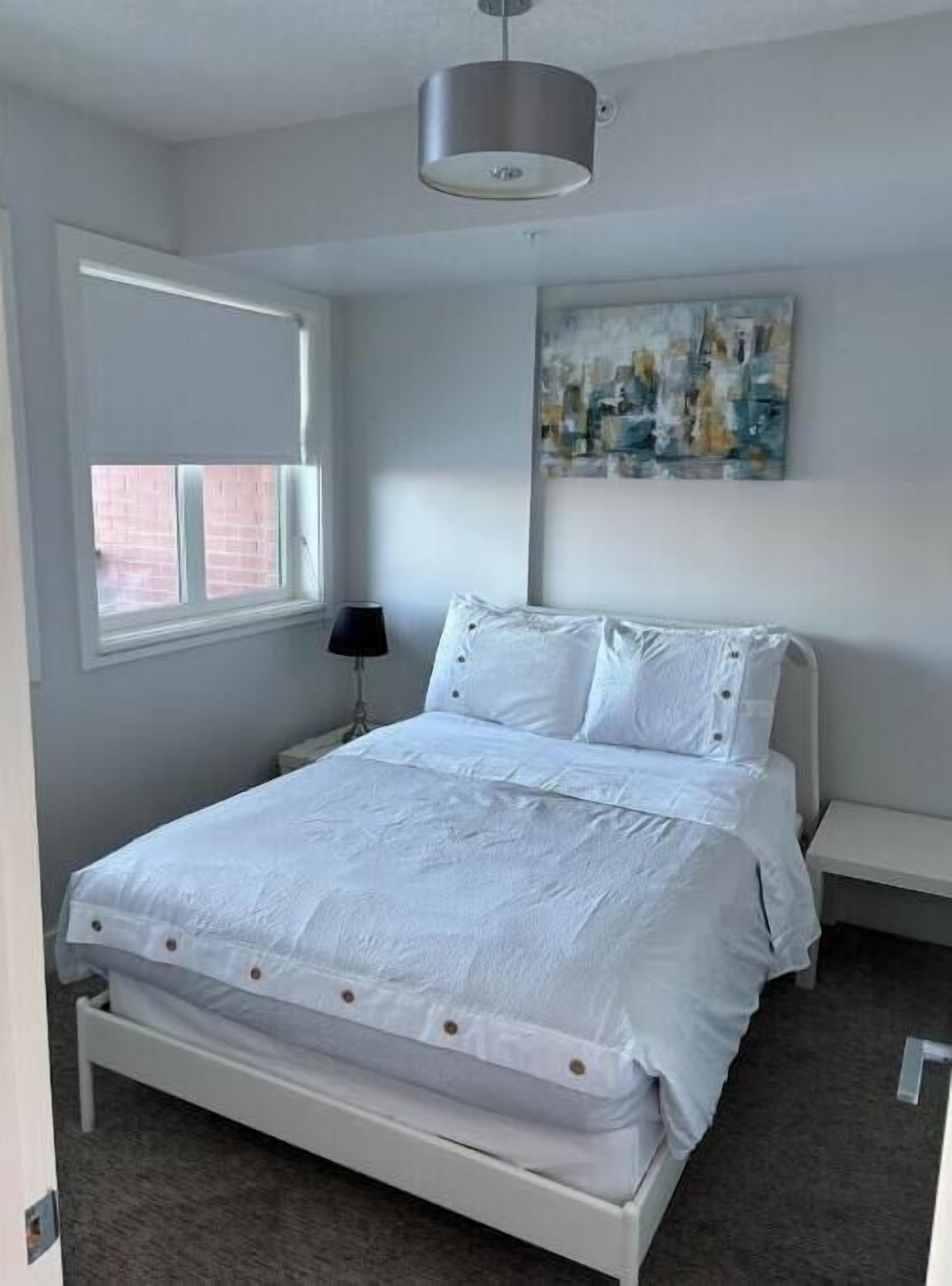 Une chambre à coucher avec un lit, une fenêtre, un tableau et une lampe.