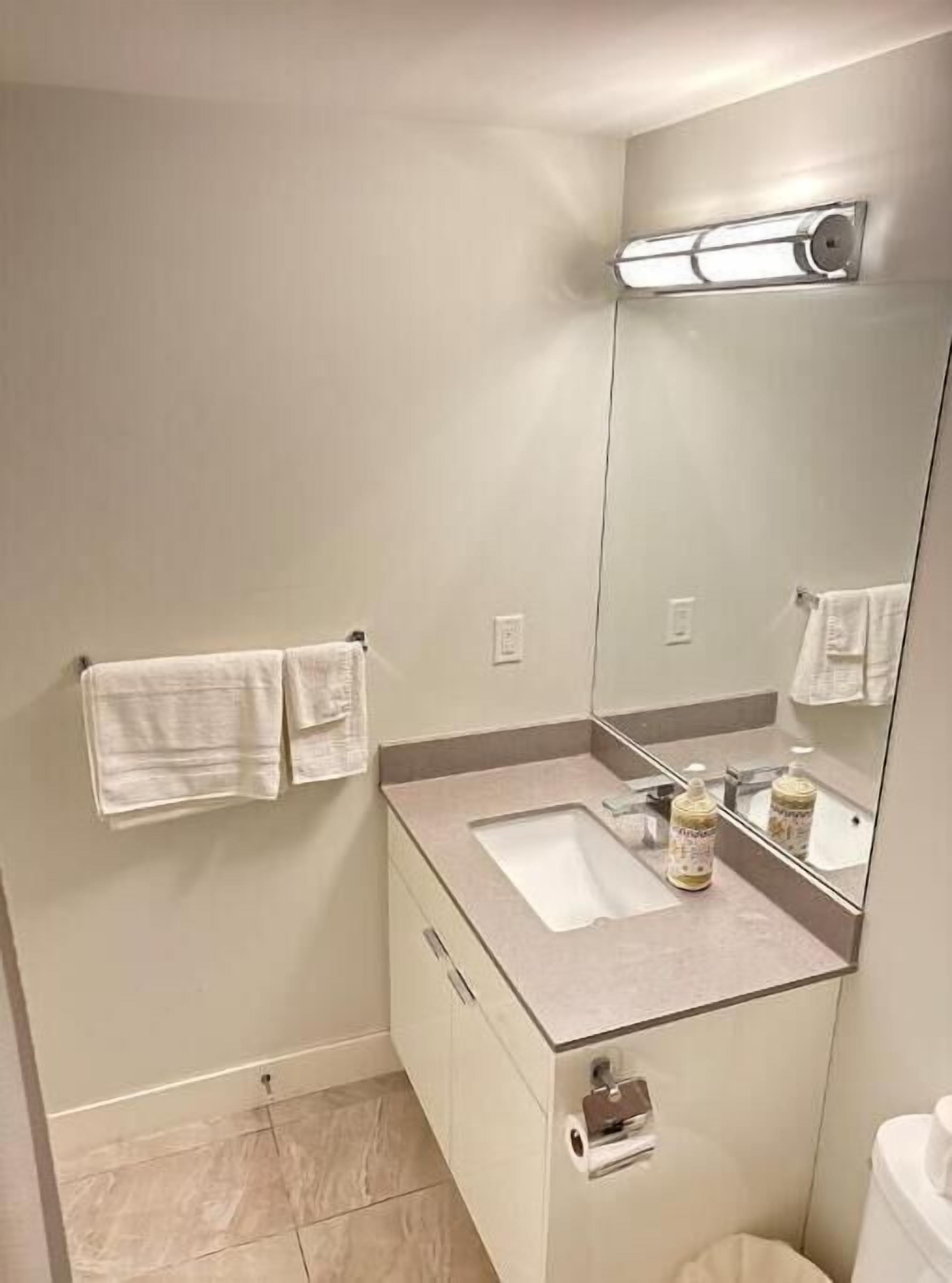 Een badkamer met een wastafel, spiegel, handdoekhouder en toilet.
