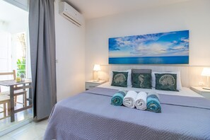 Une chambre d’hôtel avec un lit, un tableau représentant la mer et une vue sur l’extérieur.