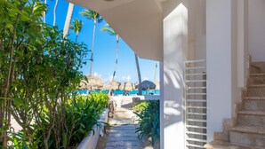 A stone staircase leading to a beach area with palm trees and a thatched-roof structure. - Comfortable & Safe Bavaro Beach Studios (Punta Cana)