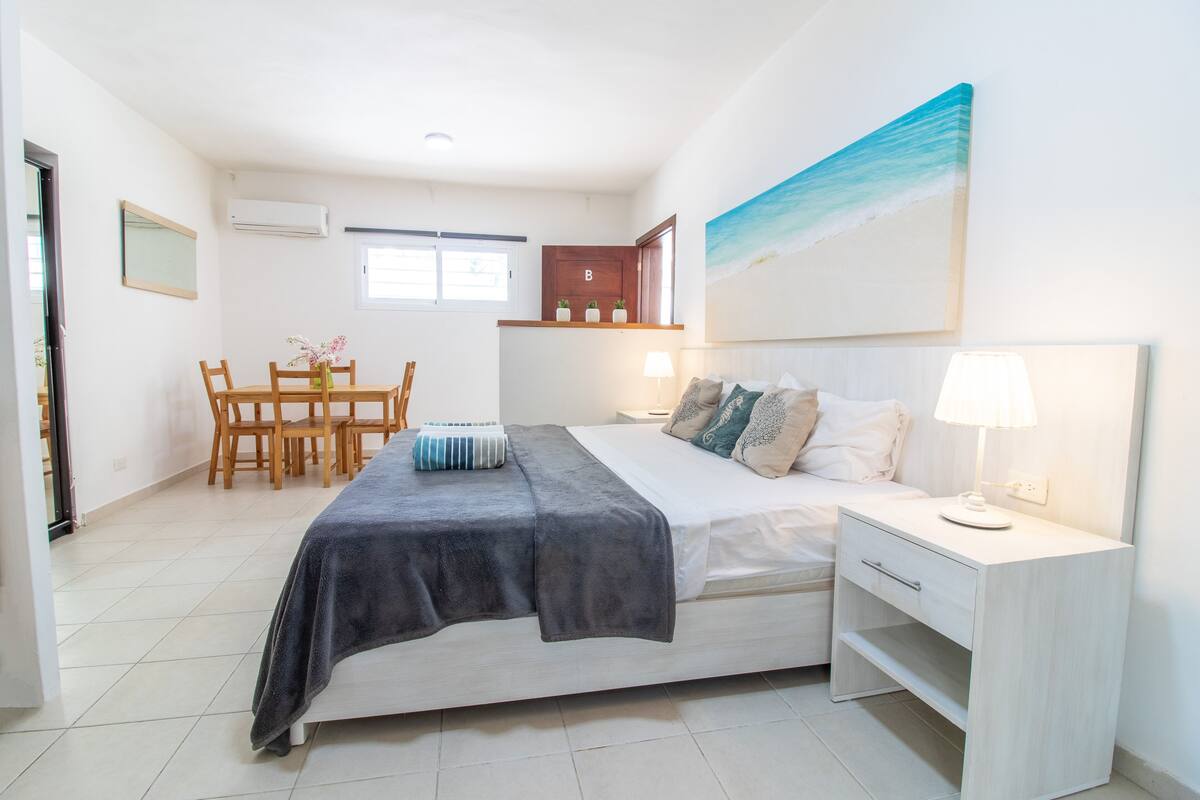 Ein Schlafzimmer mit Bett, Nachttisch, Lampe und einem Strandbild.